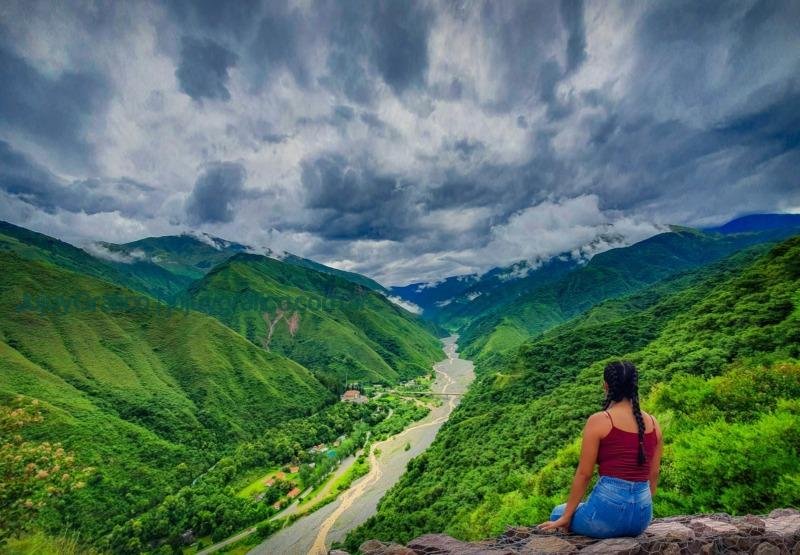 Photo by Hector Ramon Perez woman in blue tank top sitting on rock near green mountains under white clouds during daytime Jujuy Gráfico, una mirada jujeña en las noticias